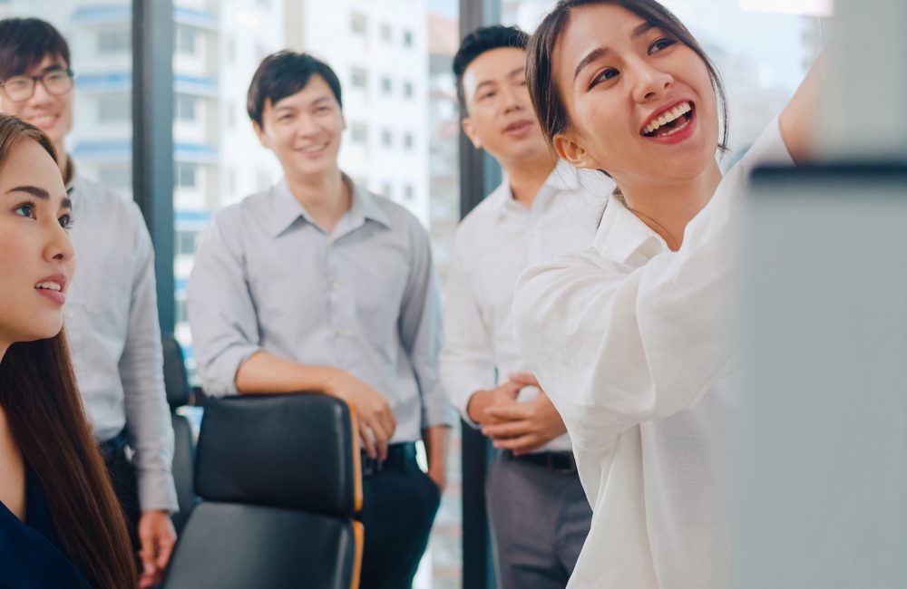 Asia businessmen and businesswomen meeting brainstorming ideas c Asia businessmen and businesswomen meeting brainstorming ideas conducting business presentation project colleagues working together plan success strategy enjoy teamwork in small modern office.