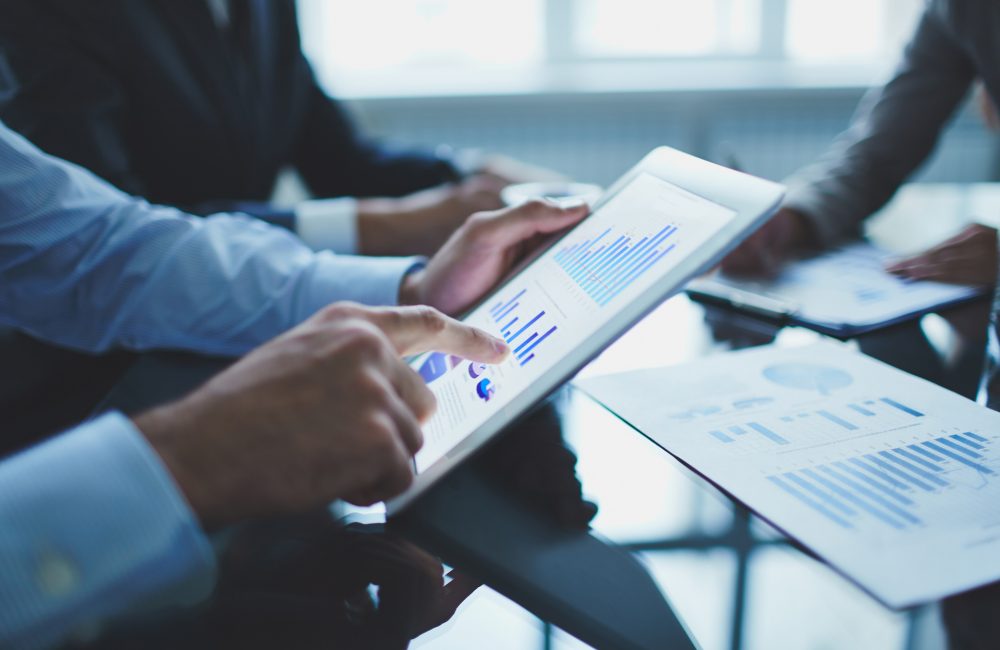 Analyzing electronic document Image of businessperson pointing at document in touchpad at meeting