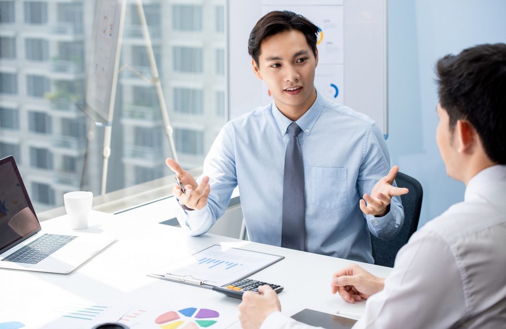 Financial broker explaning business data to his client Attractive Asian financial broker explaning business data to his client during their private meeting in the office